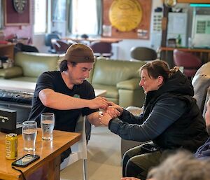 An expeditioner helps put a watch on another expeditioner