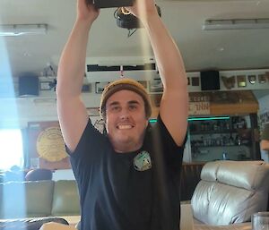 Pat holds his new watch in a box enthusiastically above his head. He is smiling.