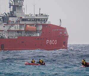 Close up of icebreaker ship with two inflatable rubber boats in the water beside the icebreaker