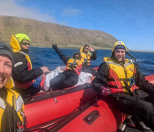 Two inflatable rubber boats together on the water, with selfie taken of the crew all wearing lifejackets and black drysuits