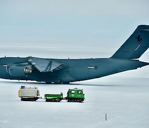 Image of RAAF C17 aircraft on ice runway with a Green Hagglund adjacent. Background shows grey sky. Foreground is snow.
