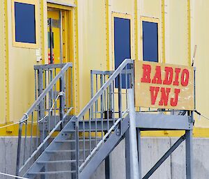 Image of Yellow Building with sign 'Radio VNJ' - This is the Operations Building at Casey Station.