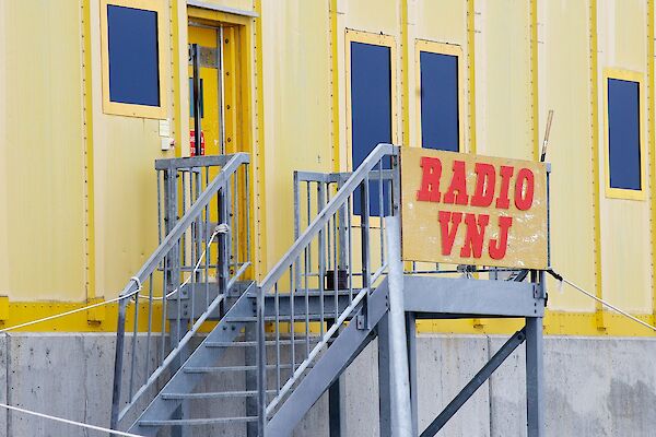 Image of Yellow Building with sign 'Radio VNJ' - This is the Operations Building at Casey Station.