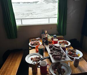 A table laid with plates of food, under a window looking out on the ice
