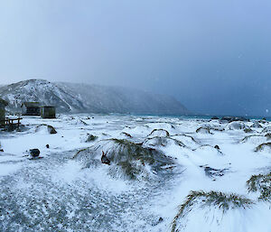 A snowy slope with a field hut on the left and ominous grey cloud ahead