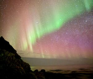 an aurora over a rocky bay
