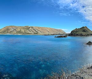 A windswept plateau in the distance, calm sea in the foreground