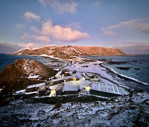 Macquarie Island station buildings, shot taken from up a hill, dusted in snow at pink dawn