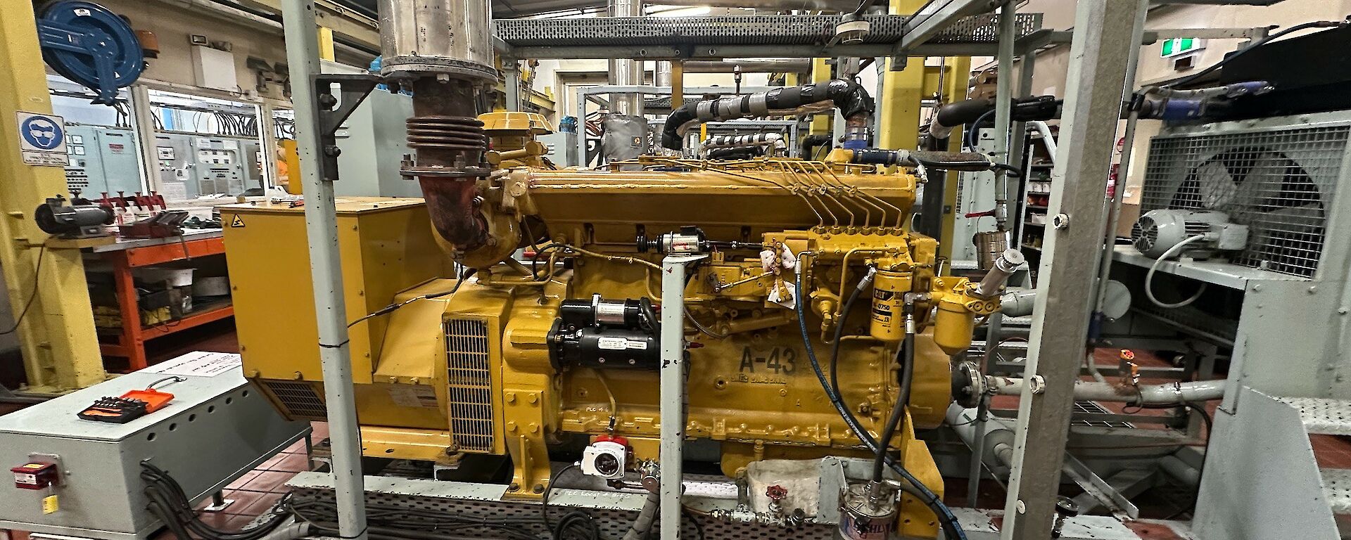 A large generator, painted yellow, surrounded by a steel frame.