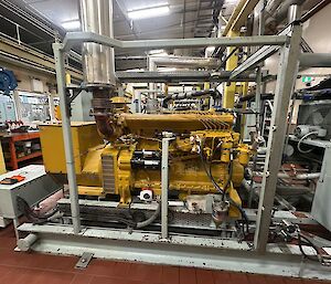 A large generator, painted yellow, surrounded by a steel frame.