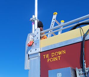 Image of expeditioner standing on ladder working on an antenna.