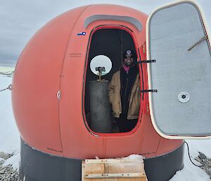 Image of expeditioner standing inside red dome room ('mag hut').