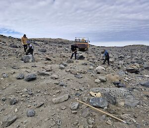 Several individuals work with rakes to restore a section of track back to its natural state.