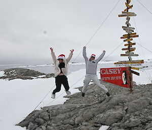 2 people jumping in the air outside in front of a sign that says Casey