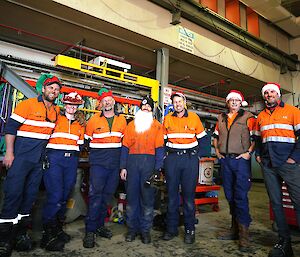 group of me in hi-vis clothing with Santa hats on in a mechanical workshop