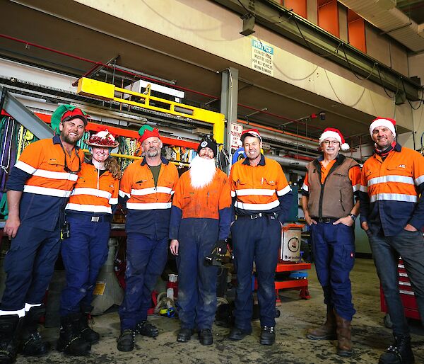 group of me in hi-vis clothing with Santa hats on in a mechanical workshop