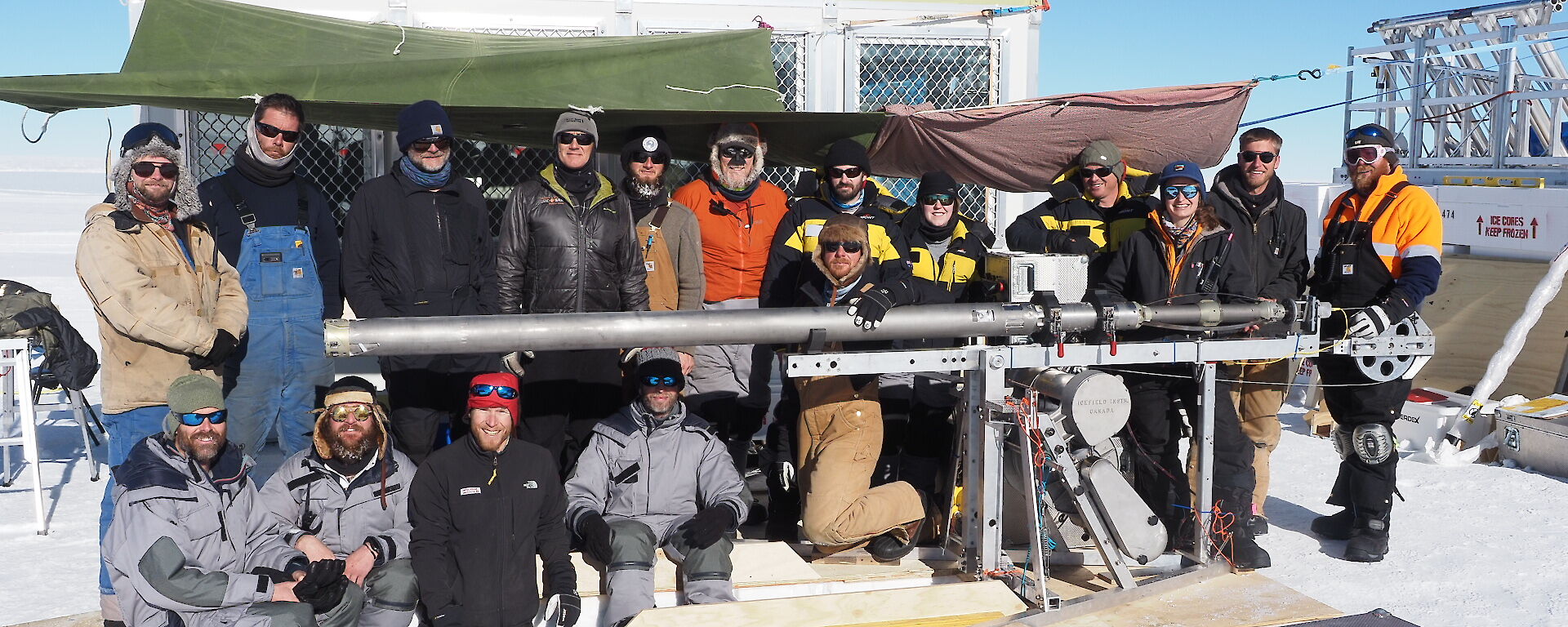 Group of 17 expeditioners posing for a photo outside at a field camp