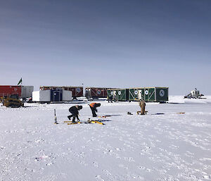 Three scientists mark out the drill shelter base frame with coloured pegs