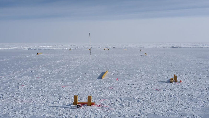 Orange and yellow markers set out on the white ice area for drilling