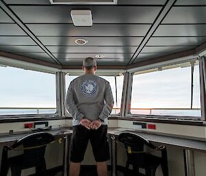 Louis standing in the crow's nest of RSV Nuyina looking out over the distant open sea