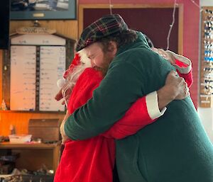 A man dressed as Santa giving a hug to another man