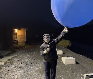 A large blue weather balloon held by a man