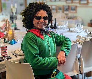 A man dressed as a Christmas elf wearing a green top and red legings
