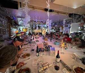 People sitting at a large fesstive table eating Christmas lunch