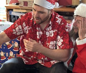 A man in a red Hawaiian shirt and a red Santa hat