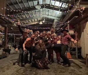 A group of people in a shed posing under festive lights