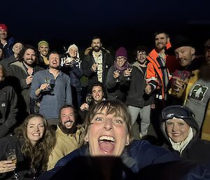 A group of men and women smiling for the camera on a dark New Year's Eve