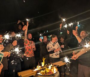 A group of people including men and women holding sparklers