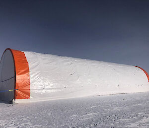 A huge, cylindrical tent-like structure, covered in an orange and white tarpaulin.