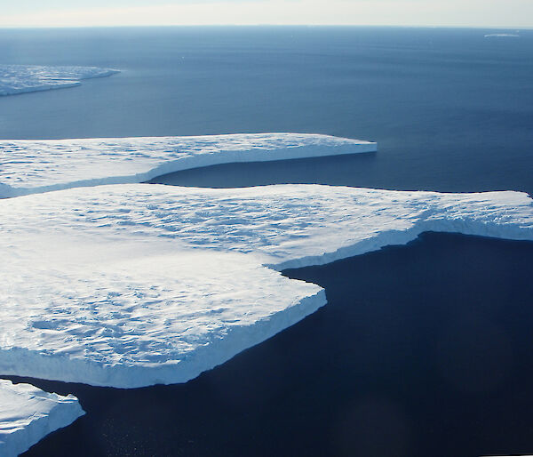 A thick ice shelf floating on a dark blue ocean.
