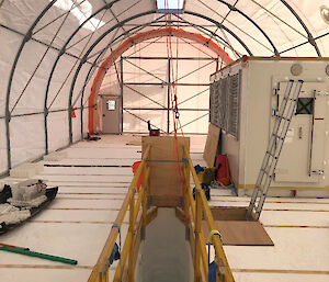 A trench and working space inside a large tent.
