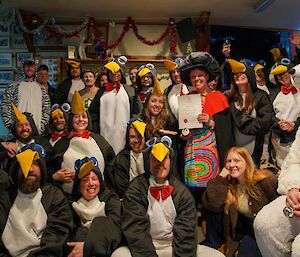 A group photo with most participants dressed in penguin costumes, but one in a polar bear outfit and one as a zebra