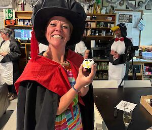 Graduate wearing robes and oversized bonnet shows cupcake to camera and smiles a very big smile