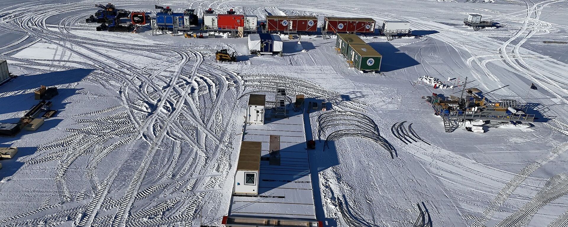 Aerial view of the ice core campsite showing shipping containers, tractors and the foundations for a large drilling shelter