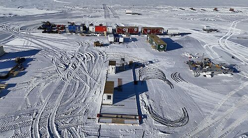 Aerial view of the ice core campsite showing shipping containers, tractors and the foundations for a large drilling shelter
