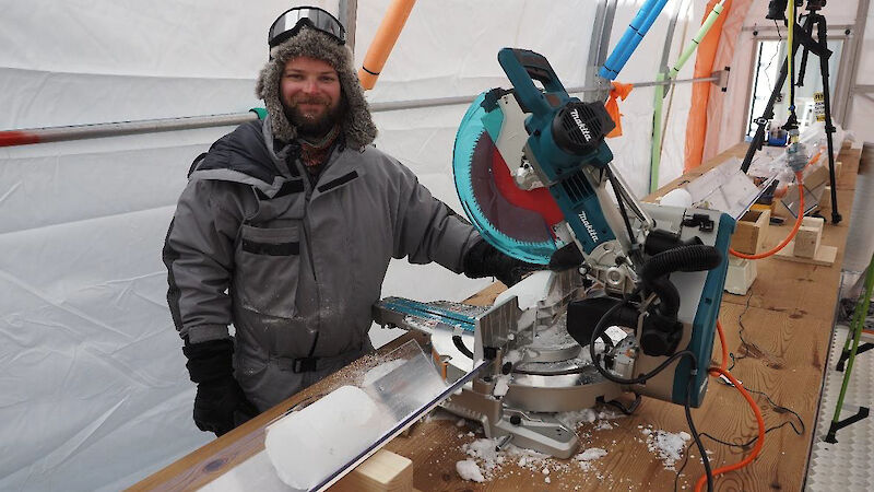 A man standing beside a circular saw used to cut pieces of ice core