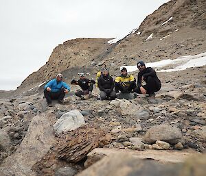 Five people on a rocky slope smiling at the camera