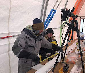 Two people using a tape measure to measure the length of an ice core