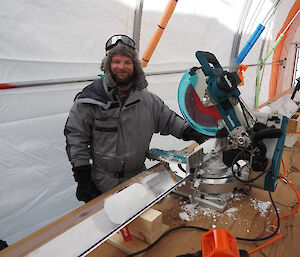 A man standing beside a circular saw used to cut pieces of ice core