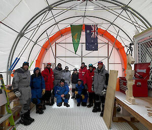 A group of people posing for a photo inside a semi-circular tent.