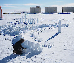 A woman placing blocks of ice in a circle to follow the progress of the sun