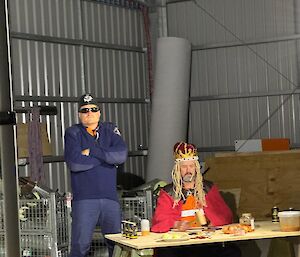 A man dressed as a judge sitting at a desk in a warehouse
