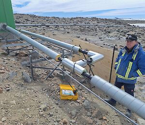 A man looks at some piping on a rocky, gravelly landscape