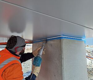A man in high vis does some welding on a concrete looking pillar