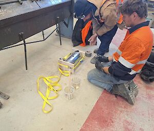 Two tradies inspect some yellow cabling on the floor