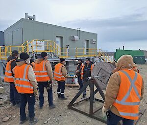 A bunch of tradies in hi vis near a big cable reel